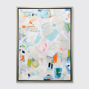 A white, beige, blue and orange abstract print in a silver floater frame hangs on a white wall.