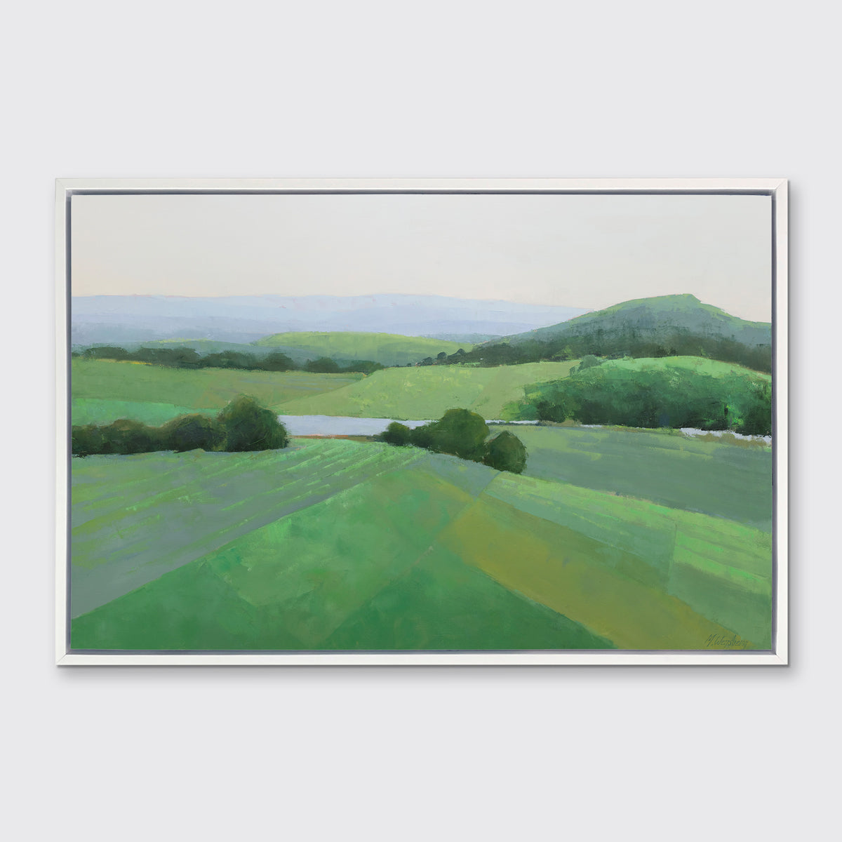 A green landscape art print framed in a white floater frame hangs on a white wall.
