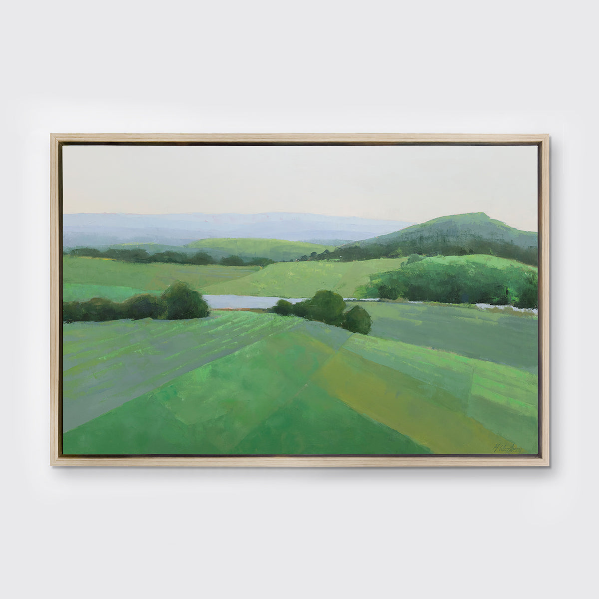 A green landscape art print framed in white oak floater frame hangs on a white wall.