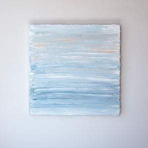 An abstract painting with thick impasto brushstrokes of blue, white, teal and a touch of orange paint is hung on a gallery wall.