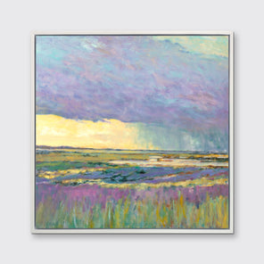 A multicolored abstract landscape print in a white floater frame hangs on a white wall.
