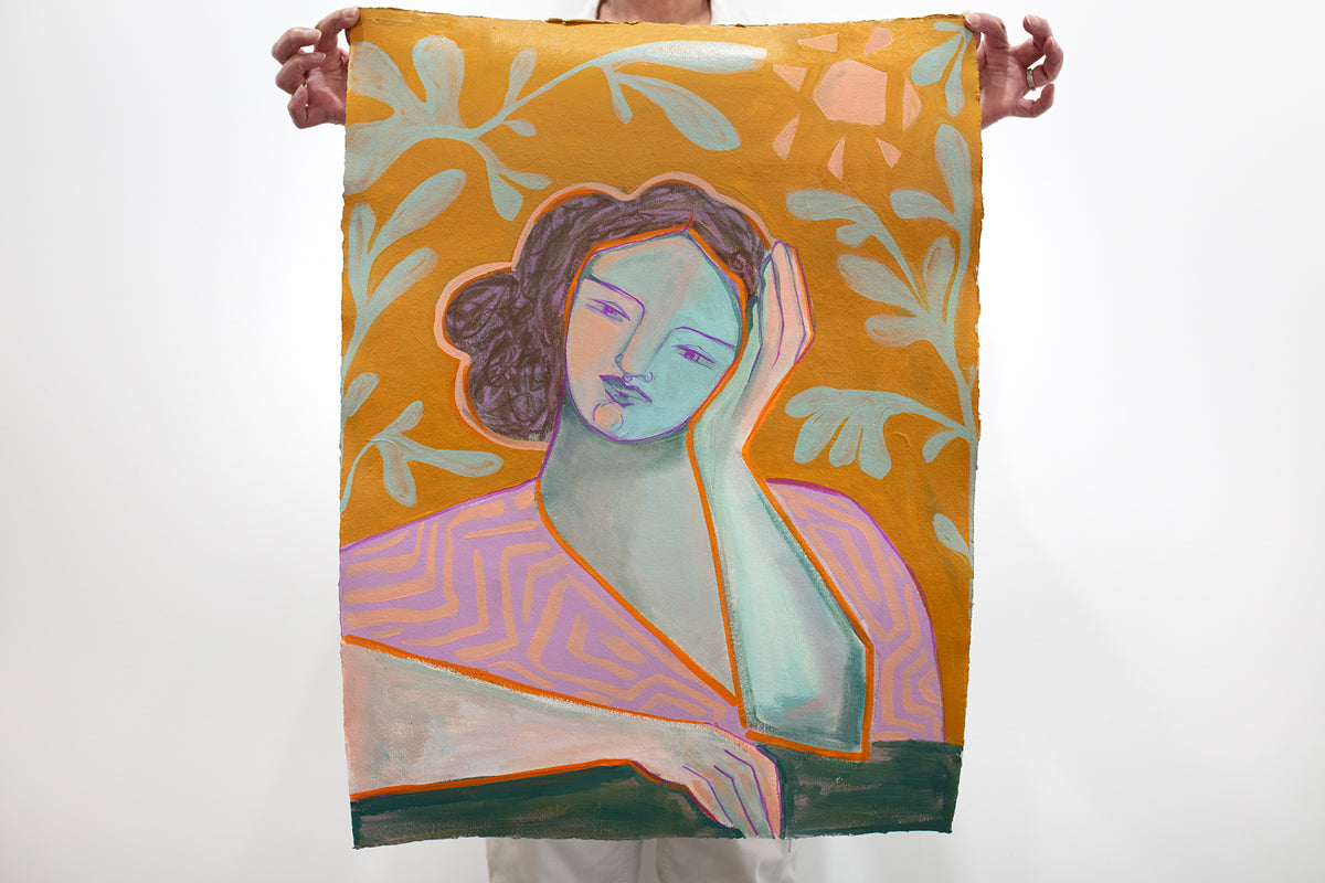 A person holds a yellow-gold and pink abstracted figure painting in front of a white wall. 