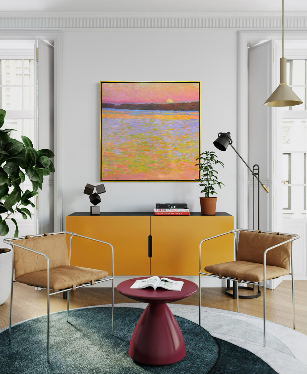 Framed painting of a sunset over water with a colorful sky hanging over a colorful modern orange credenza.