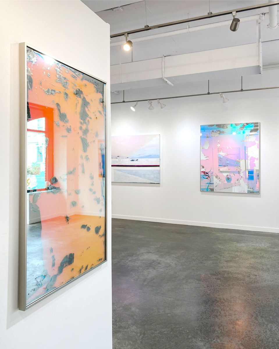 Three abstract artworks hang on white walls in an art gallery. 