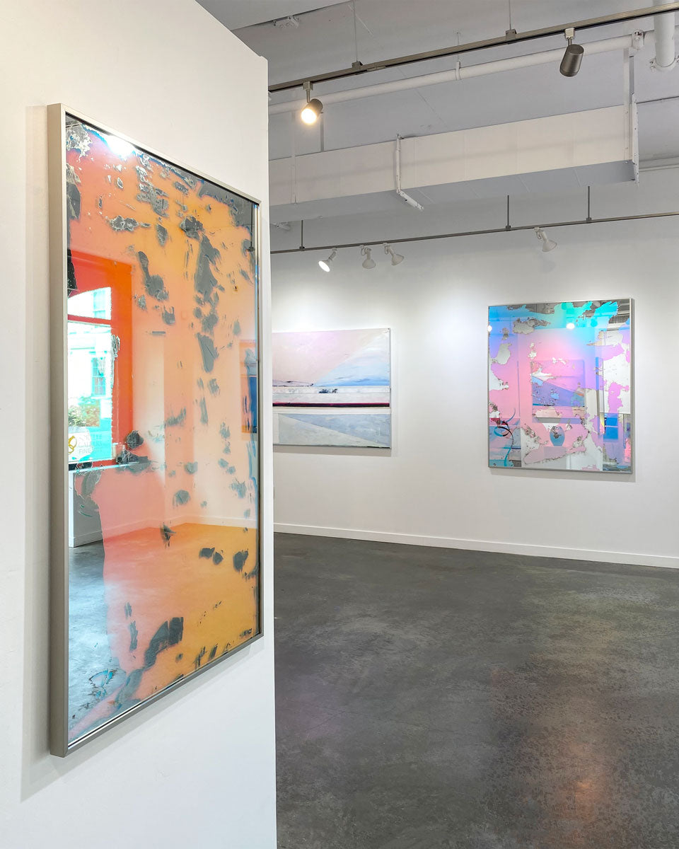 Three abstract artworks hang on a white wall in an art gallery. 