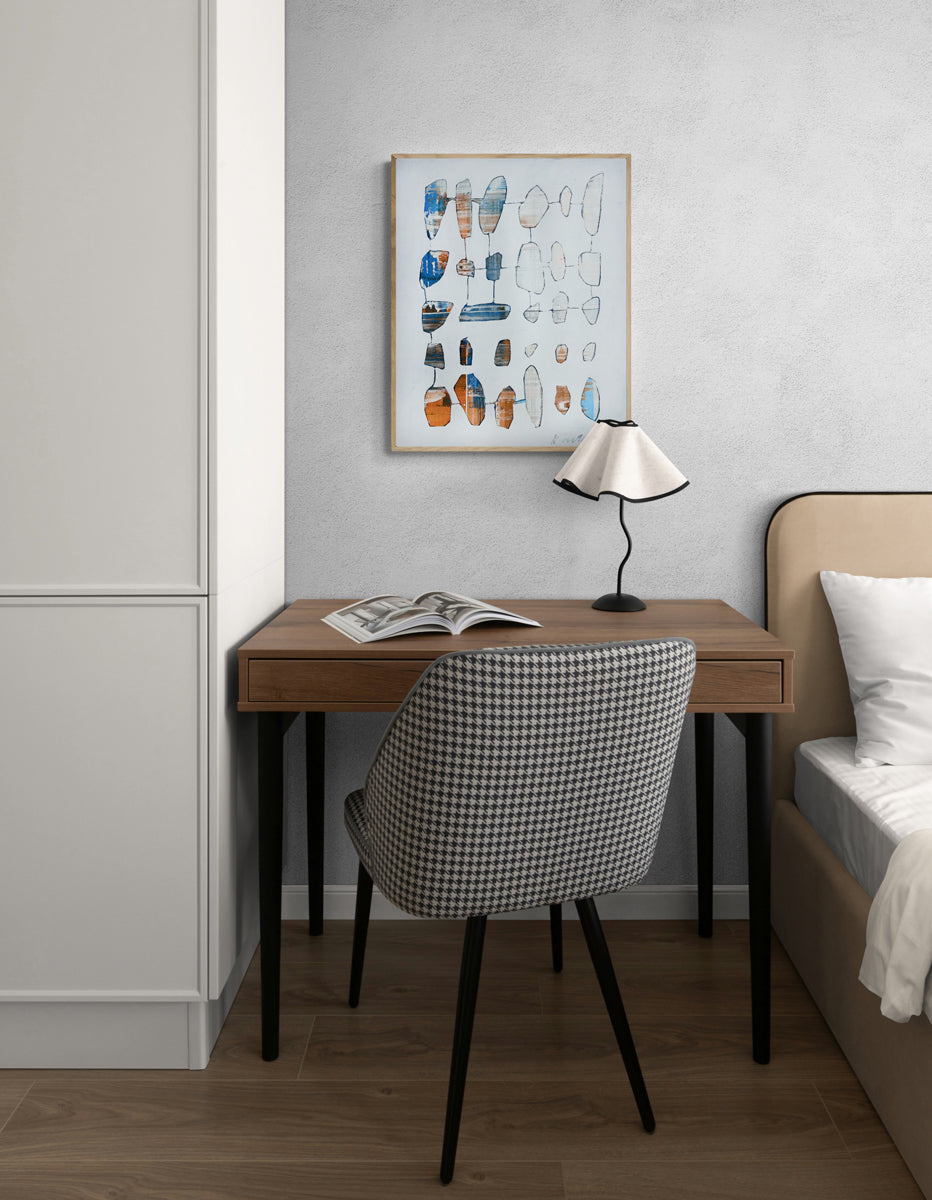 Small home office with a desk, chair, and framed artwork on a gray wall.