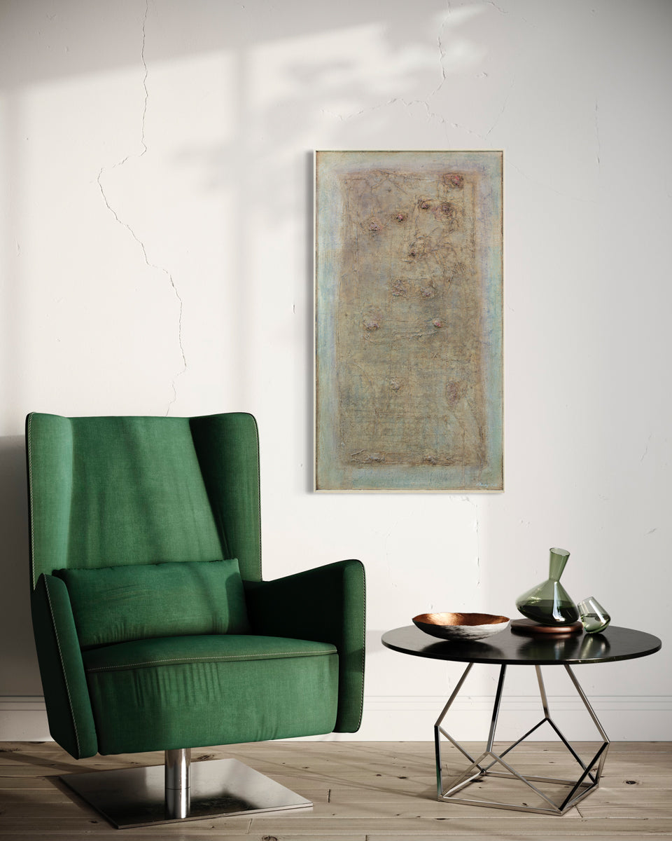 A green and brown abstract painting hangs on a white wall above an emerald green armchair and a modern black end table with glass and ceramic table decor. 
