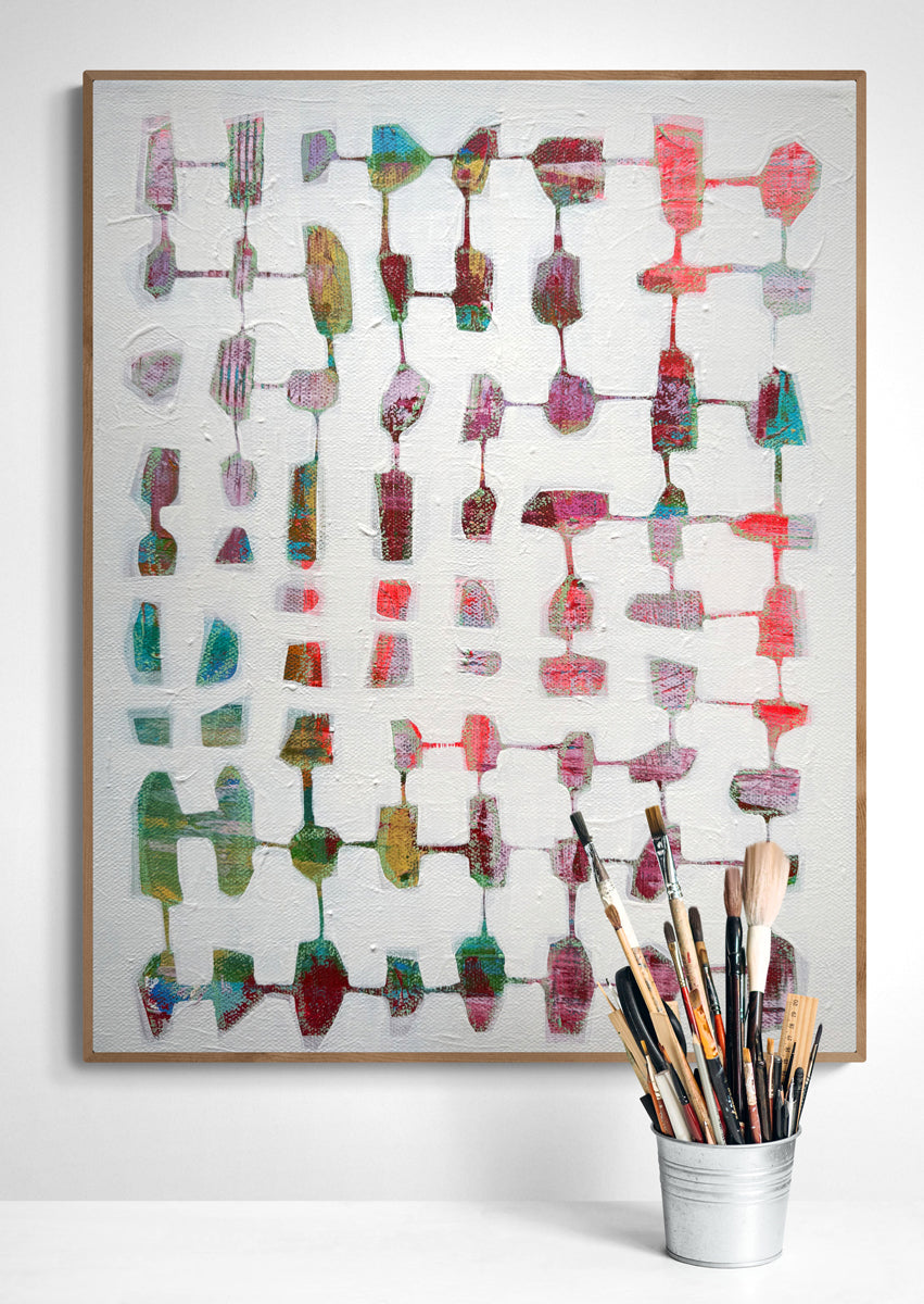 Colorful abstract art piece on a white wall with a cup of paintbrushes below.