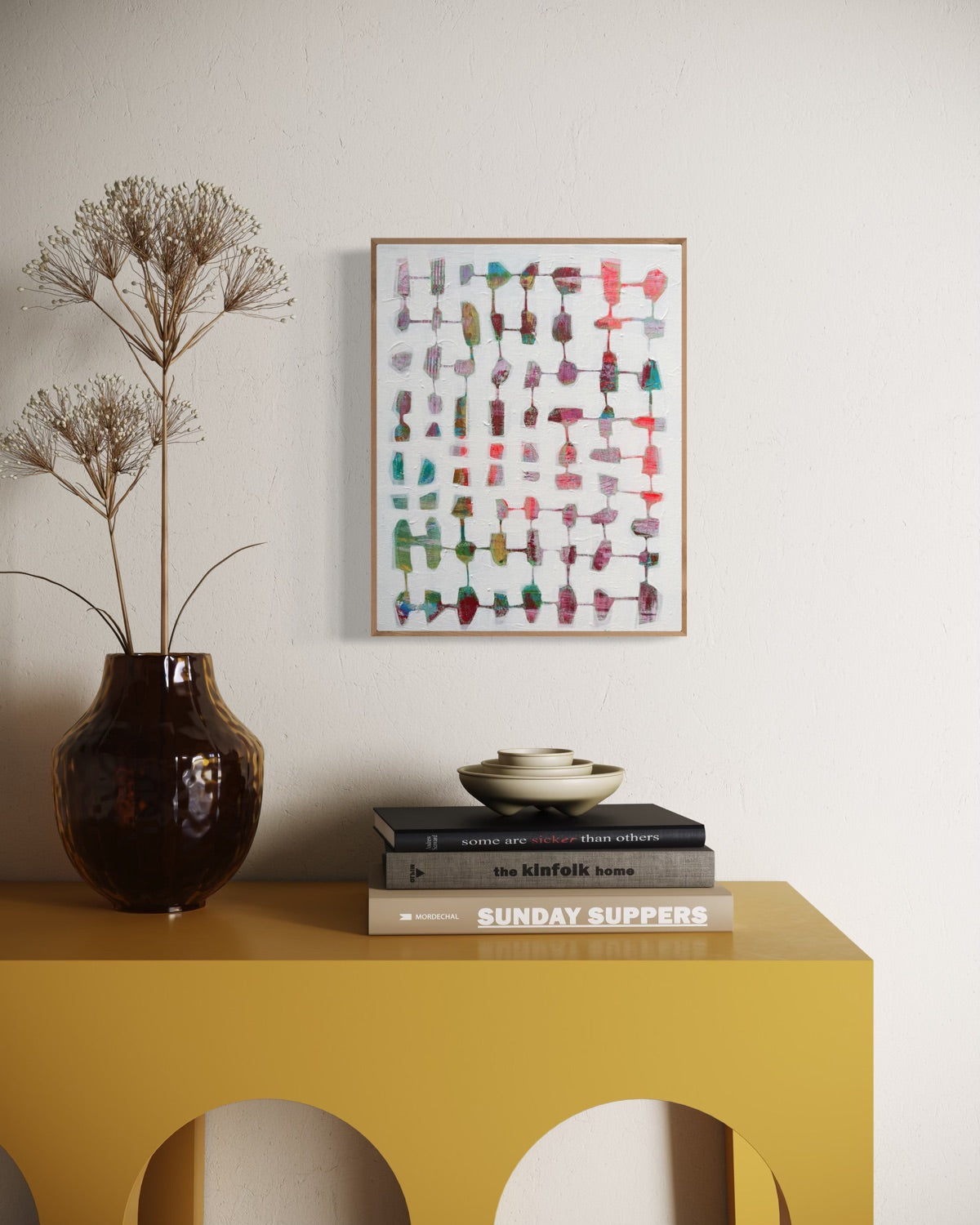 Yellow console table with decorative items including a vase, books, and a framed artwork on a plain wall.