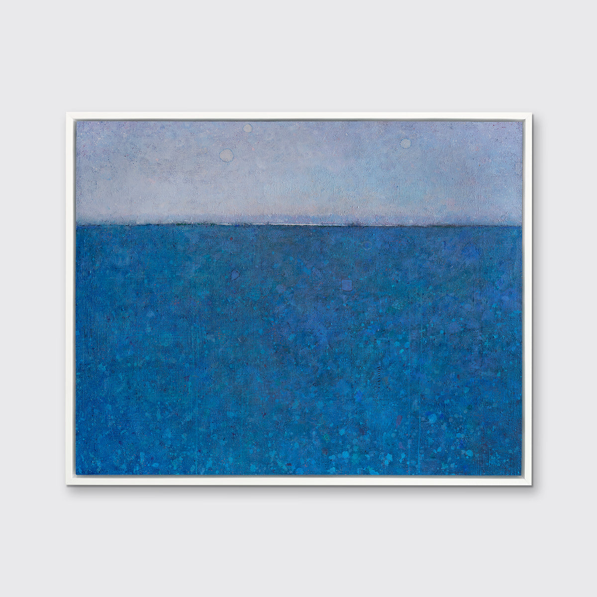A deep blue abstract landscape print in a white floater frame hangs on a white wall.
