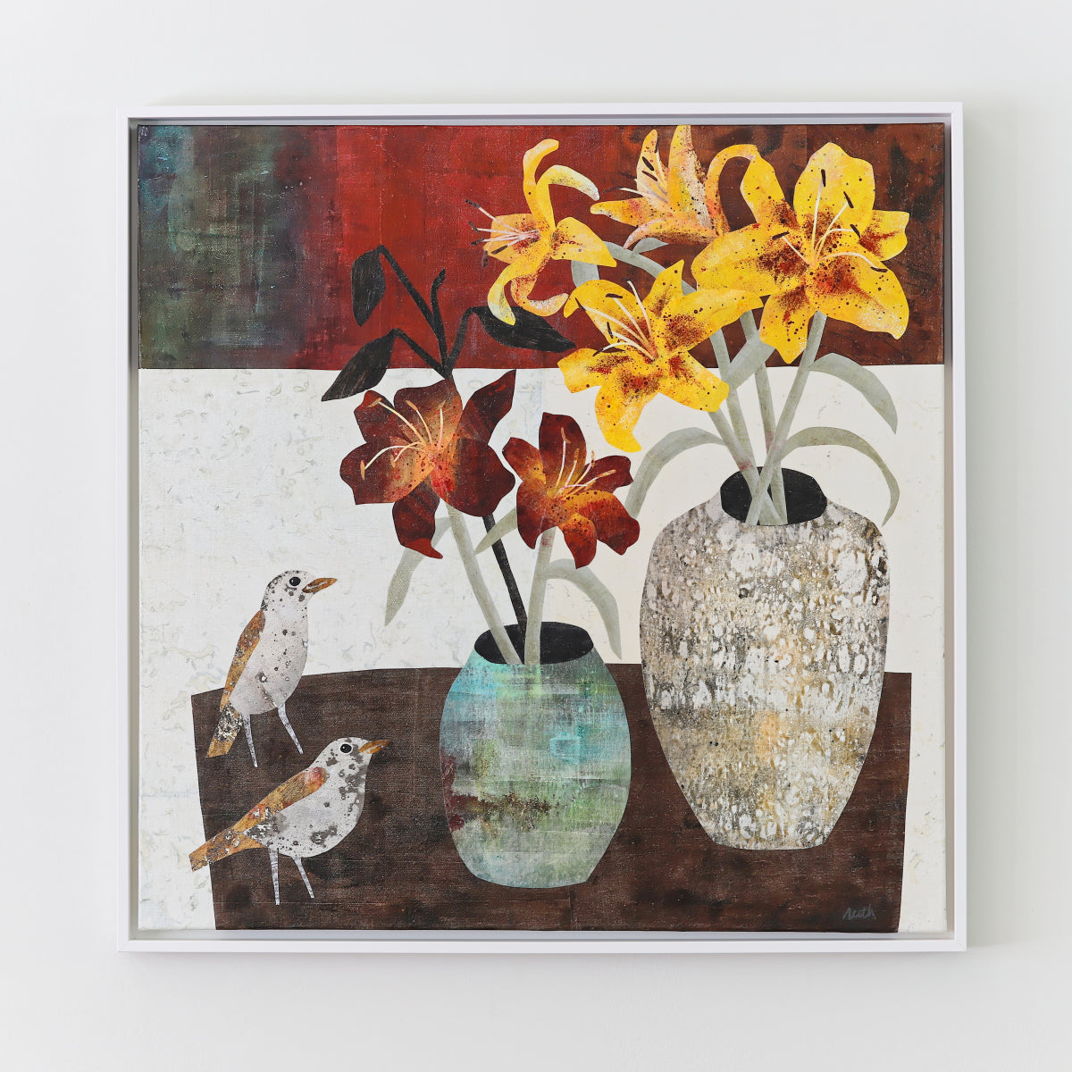 A framed square collage painting featuring a still life scene with yellow and red flowers in two vases, plus two small birds, shown against a light wall.
