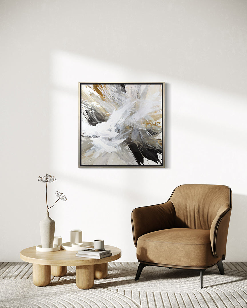 A white, umber, black, grey, yellow ocher and gold abstract print in a silver floater frame hanging on a wall over a Yellow Ocher chair and a coffee table with white ceramic pots.