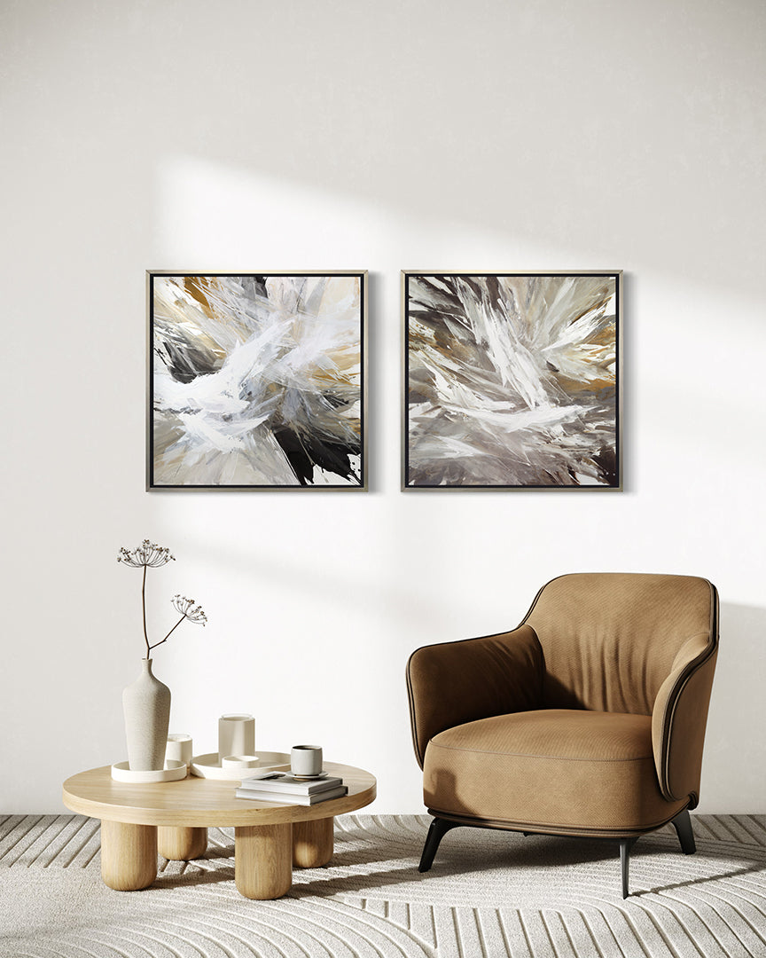 2 white, umber, black, grey, yellow ocher and gold abstract print in a silver floater frame hanging on a wall over a Yellow Ocher chair and a coffee table with white ceramic pots.