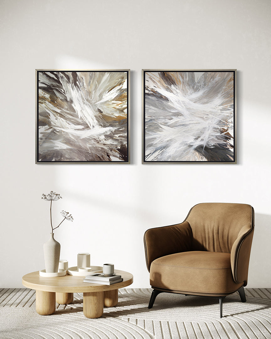 2 white, umber, black, grey, yellow ocher and gold abstract print in a silver floater frame hanging on a wall over a Yellow Ocher chair and a coffee table with white ceramic pots.