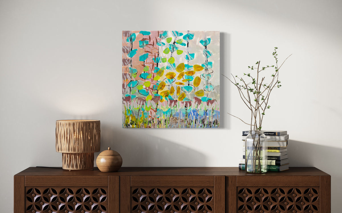 A colorful pink, orange, green, and turquoise abstract painting hangs on a white wall above a wooden console table with modern table decor and a stack of books. 