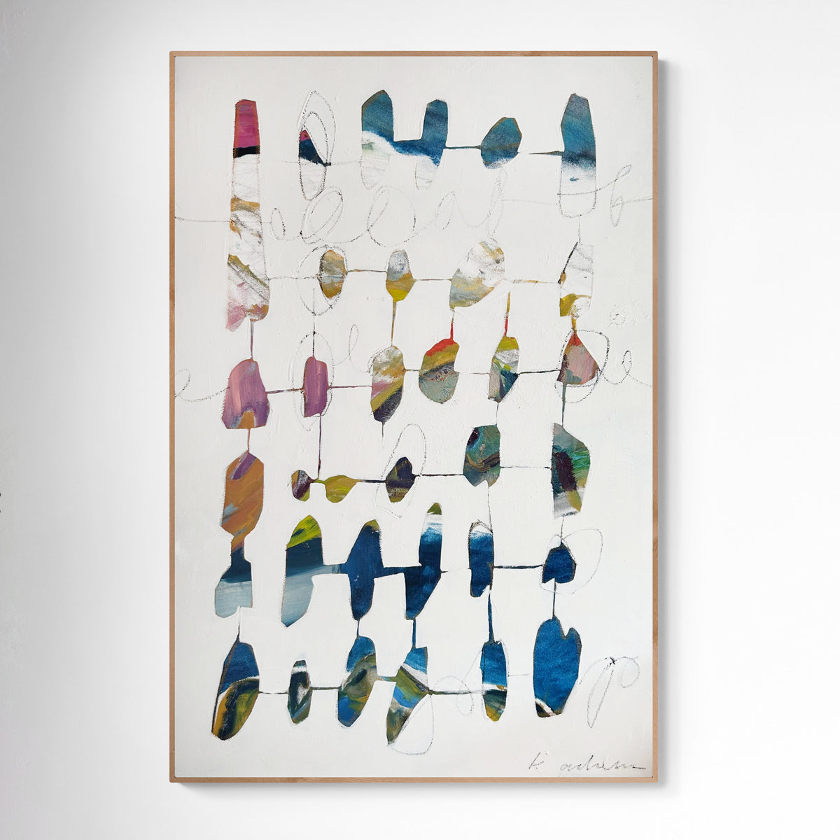 Abstract art piece with colorful geometric shapes in a wood frame on a white wall.