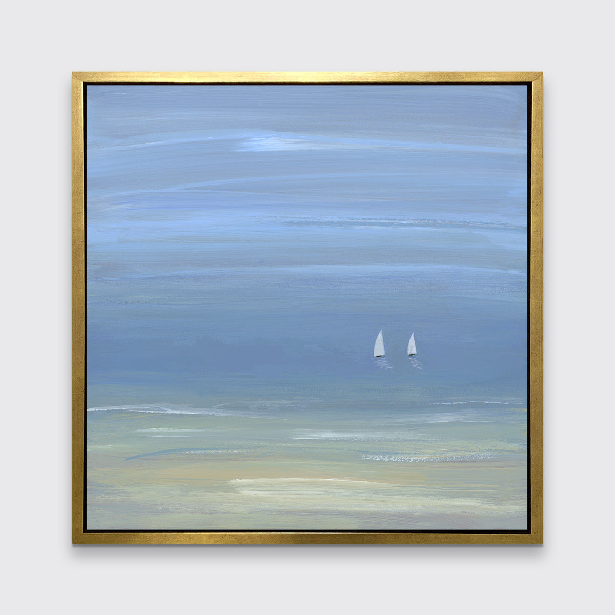 A blue, beige and white abstract seascape print with two small sailboats in a gold floater frame hangs on a white wall.