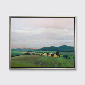A landscape print in a silver floater frame hangs on a white wall.