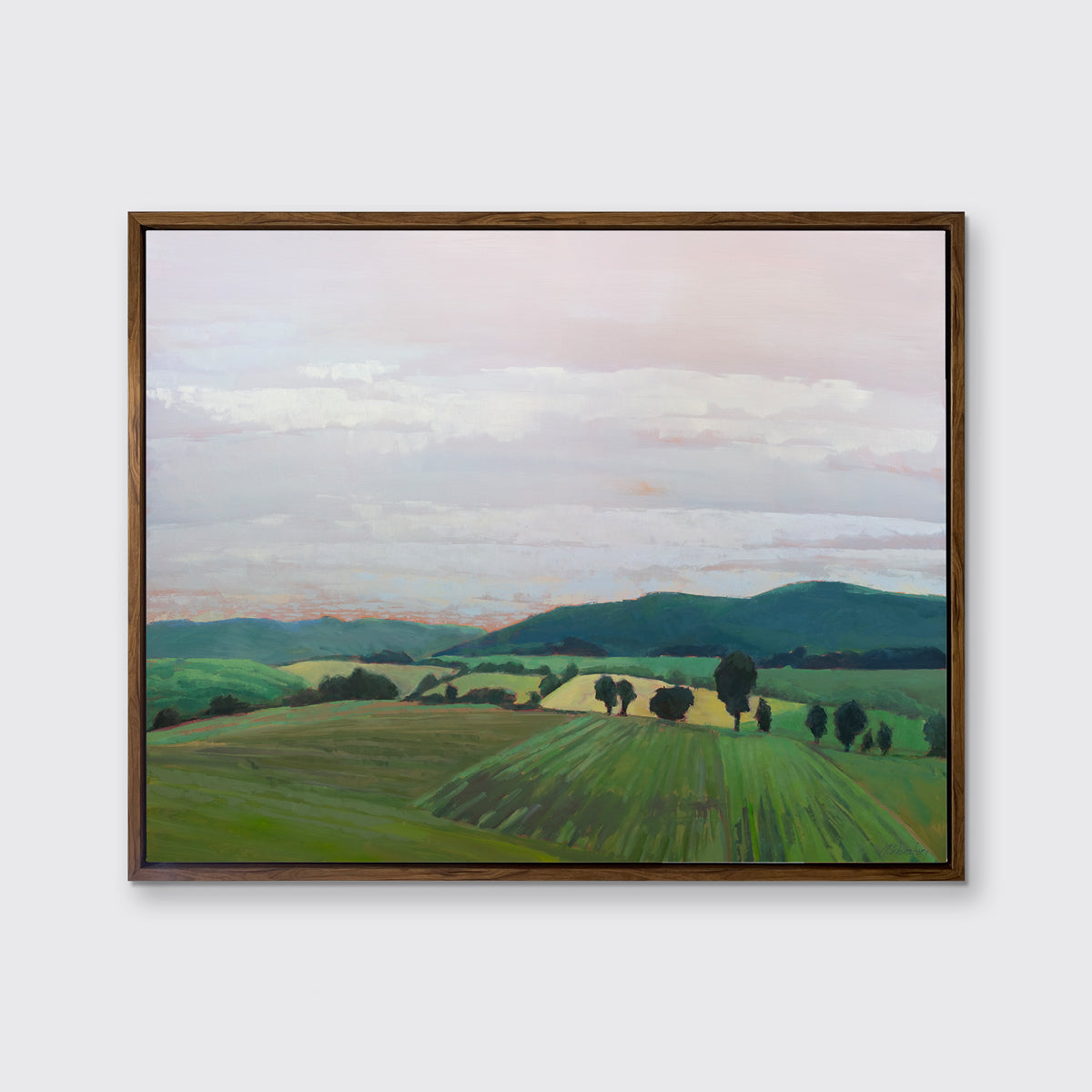 A landscape print in an oak wood floater frame hangs on a white wall.