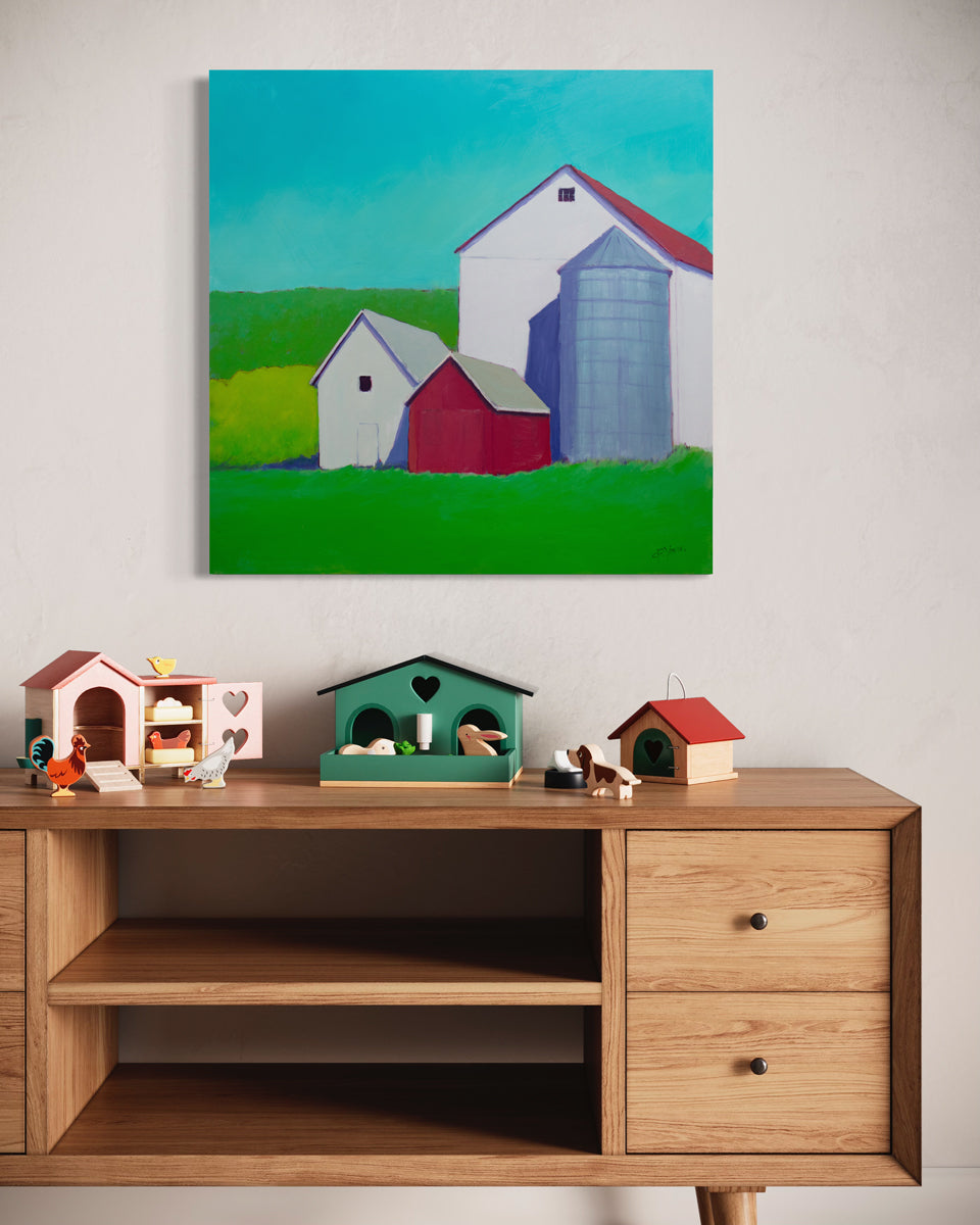A colorful landscape painting of barns hangs on a light wall above a wooden dresser with small colorful figurines. 