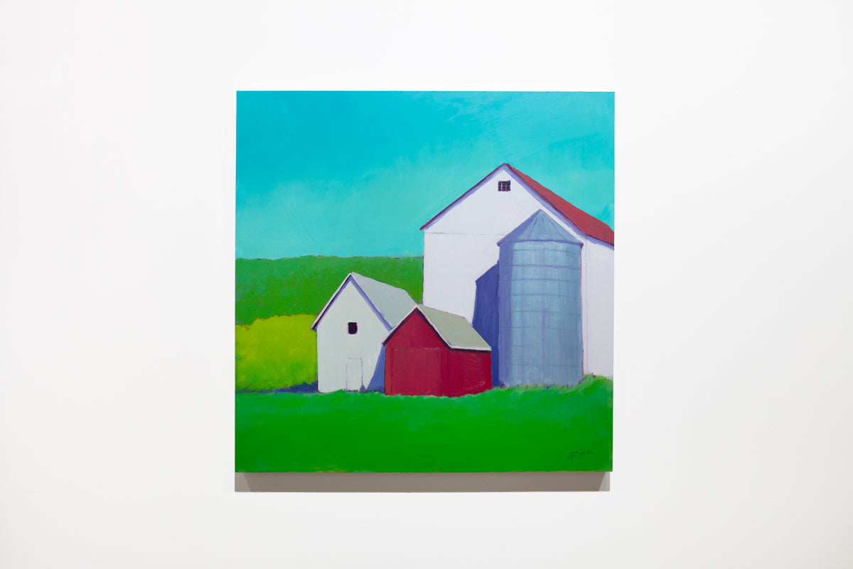 A landscape painting of white and red barns surrounded by vibrant green grass under a blue sky hangs on a white wall. 