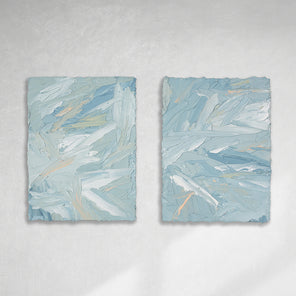 A pair of thickly painted paintings in teal, sea foam green, celadon, white and hints of orange and yellow by Teodora Guererra hang on a white wall. The two painting are like wall sculptures.