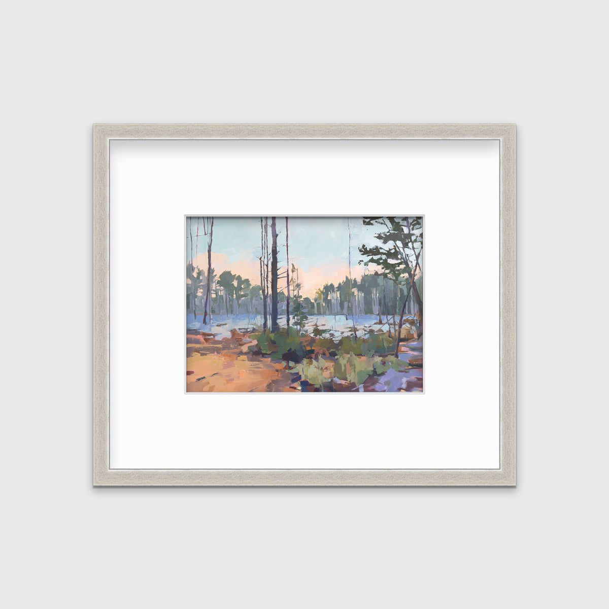 A light blue, green, brown and purple abstract landscape print in a silver frame with a mat hangs on a white wall.