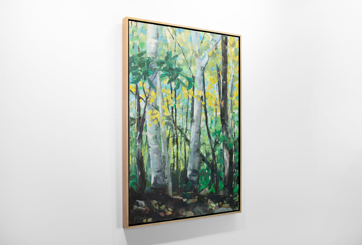 A framed green painting of a forest hangs on a white wall.