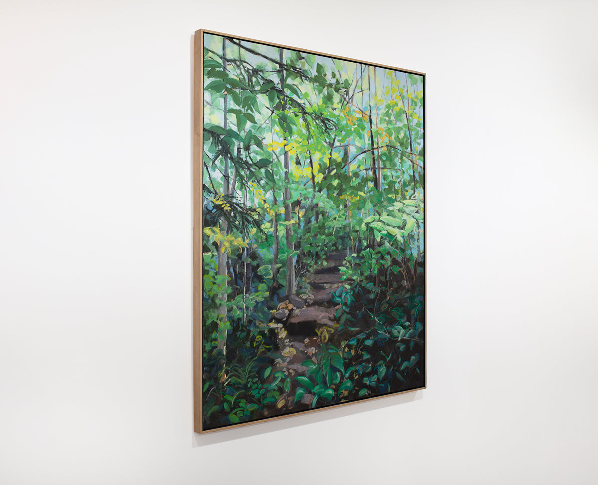 A large framed green painting of a forest hangs on a white wall.