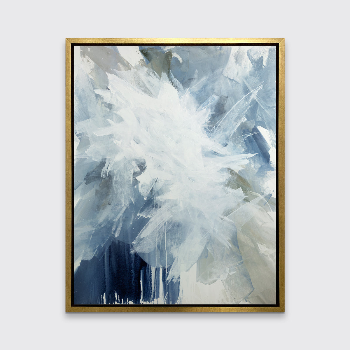 A white, blue and grey abstract print in a gold floater frame hangs on a white wall.