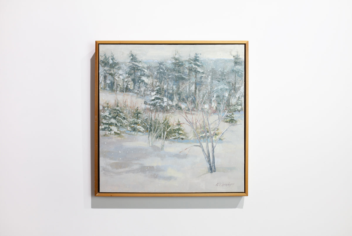 A white, grey and green snow landscape painting by Molly Doe Wensberg hangs in a light wood floater frame on a white wall.