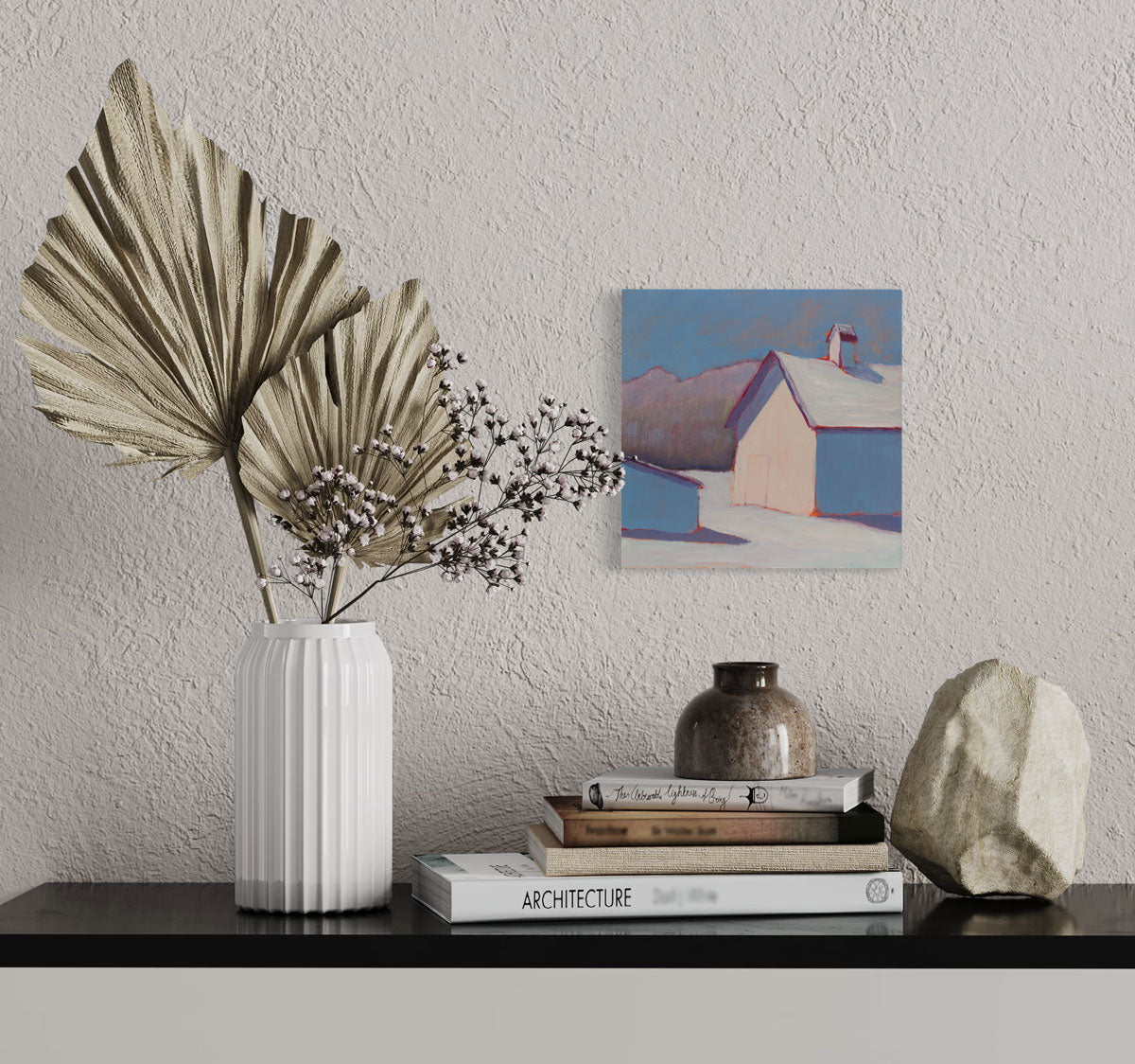A blue, white, and red contemporary landscape painting hangs on a textured wall above a console table with modern table decor. 