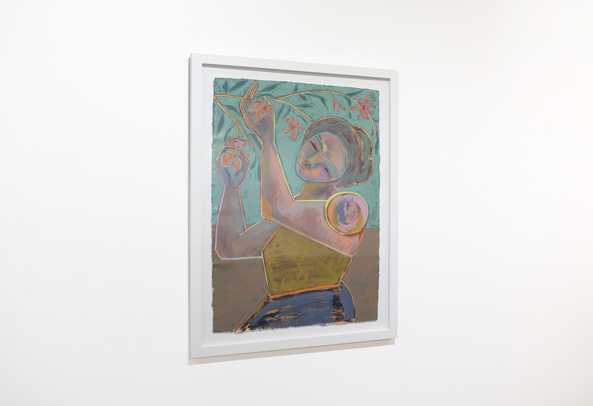 A side view of a framed abstracted blue, turquoise and yellow painting of a woman holding flowers from a branch hangs on a white wall.
