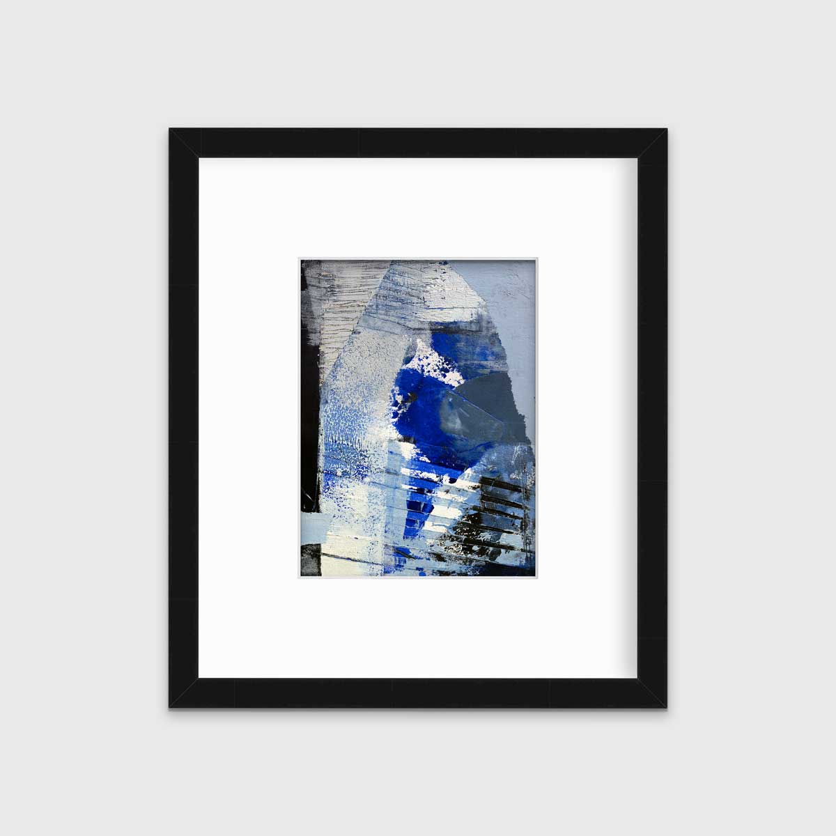 A blue, white and black abstract print in a black frame with a mat hangs on a white wall.