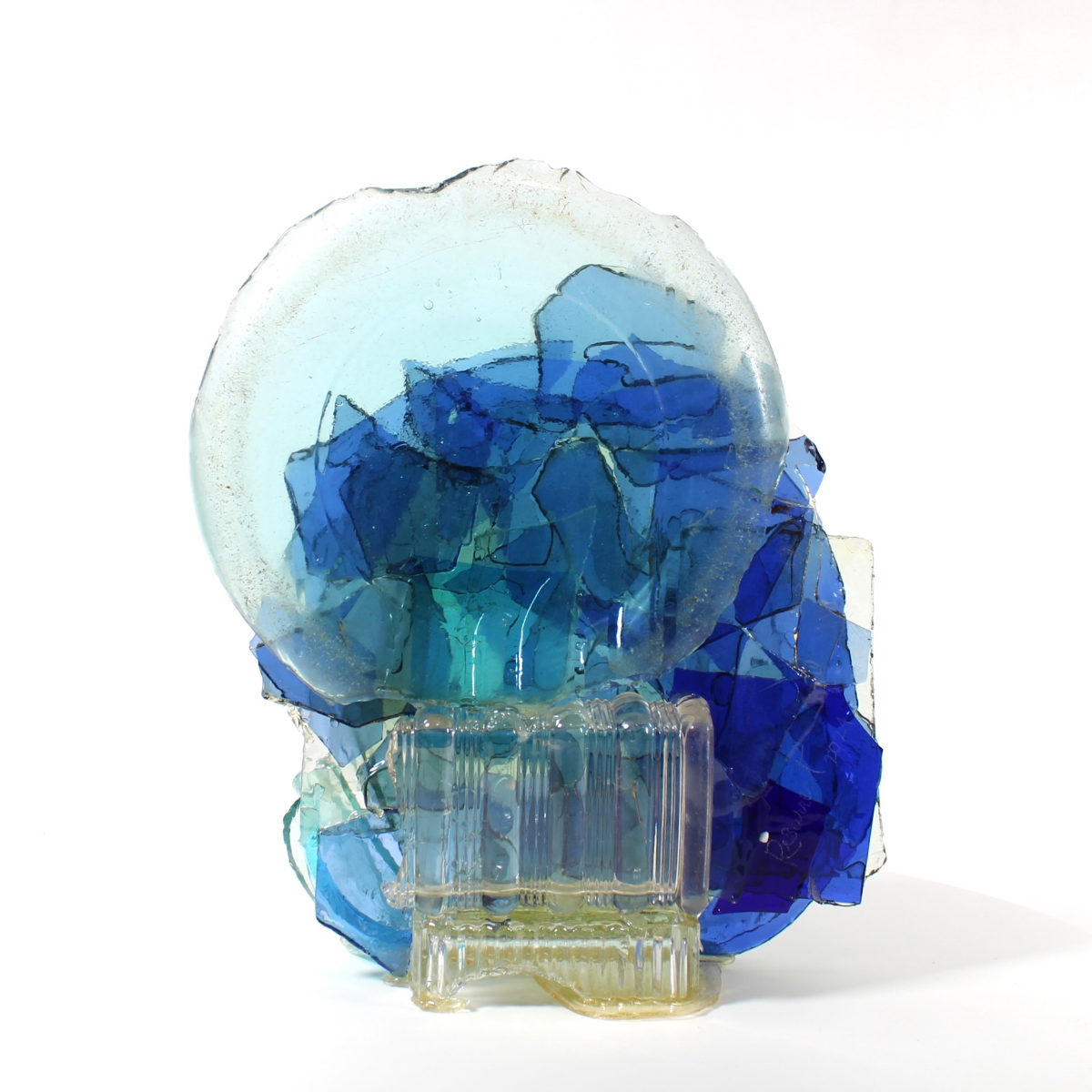 Glass sculpture made with blue and clear glass pieces on a white background.