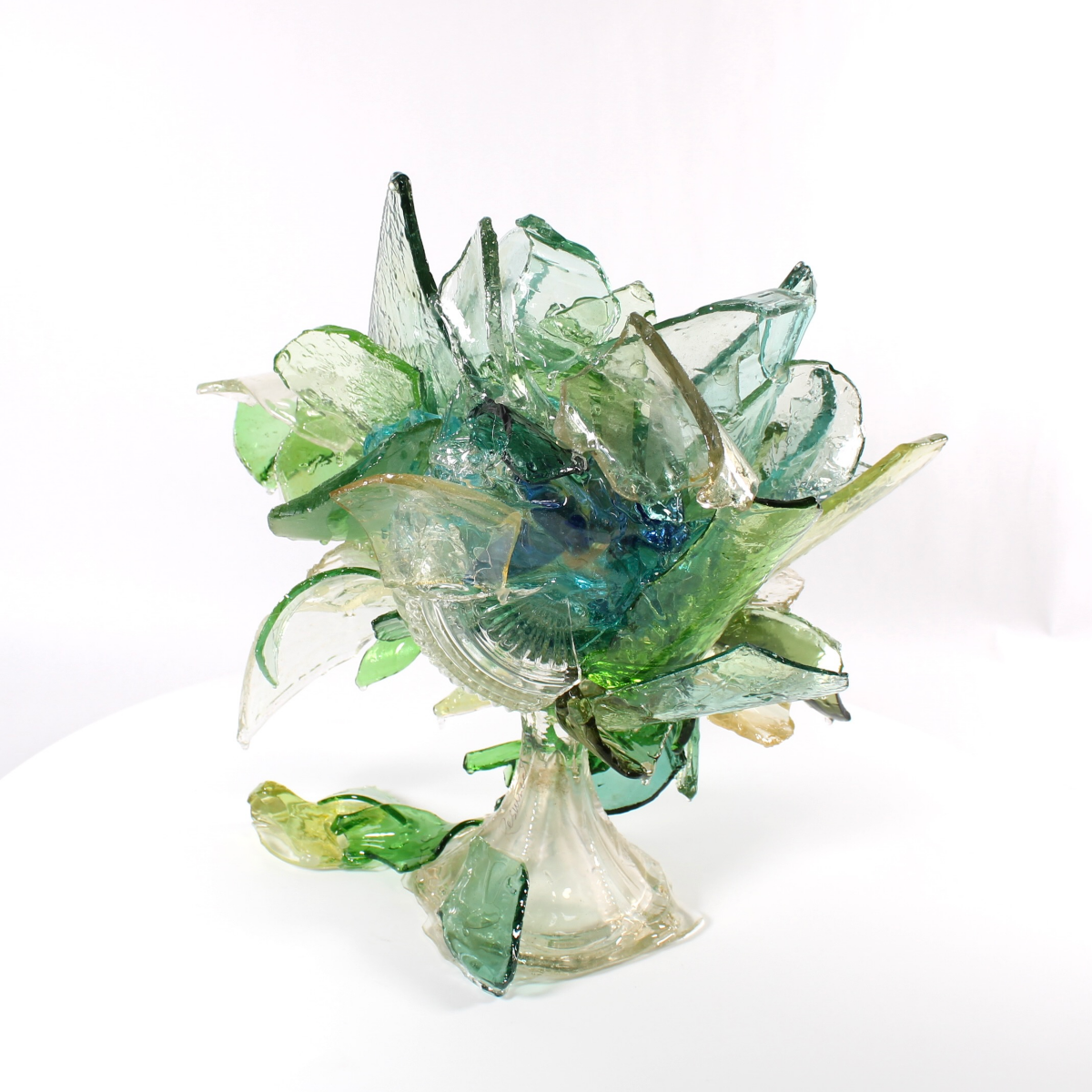 Glass sculpture of a flower with green and clear colors on a white background
