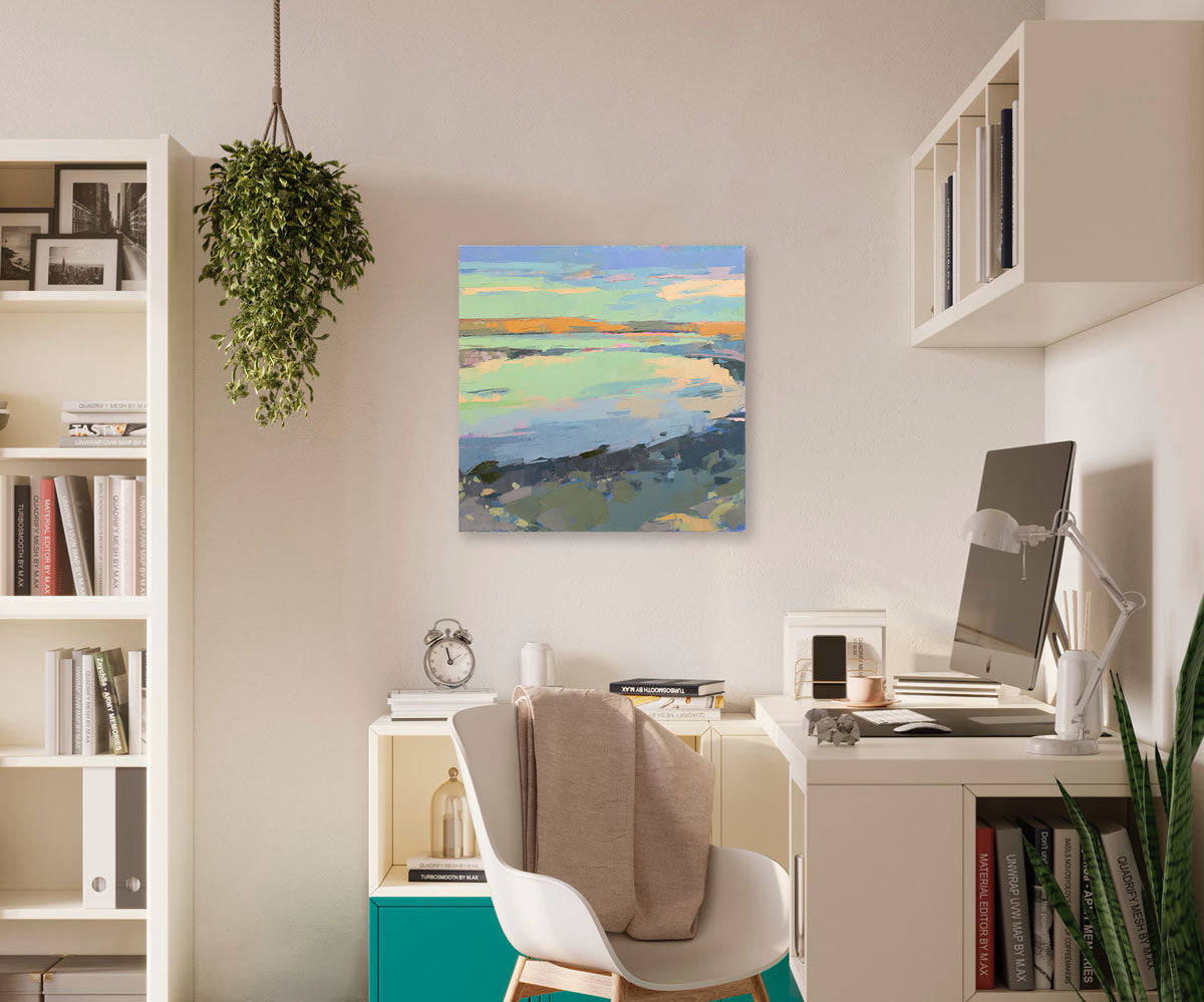 A green, blue, and pink abstract landscape hangs on a light wall above a desk and modern desk chair. 