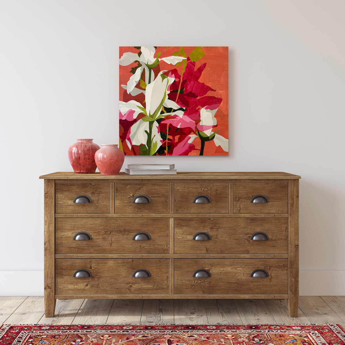 Wooden dresser with decorative items and a floral painting on a white wall.