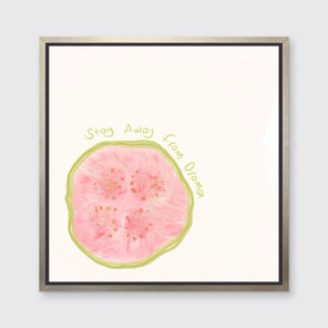 An abstract art print of a fruit framed in a silver floater frame hangs on a light wall.