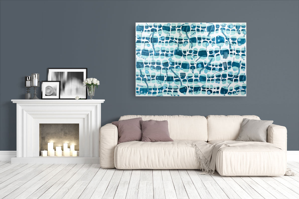 An abstract blue and white painting hangs on a deep grey wall above a cream sofa with muted pink pillows and a white fireplace with decor on the mantle. 
