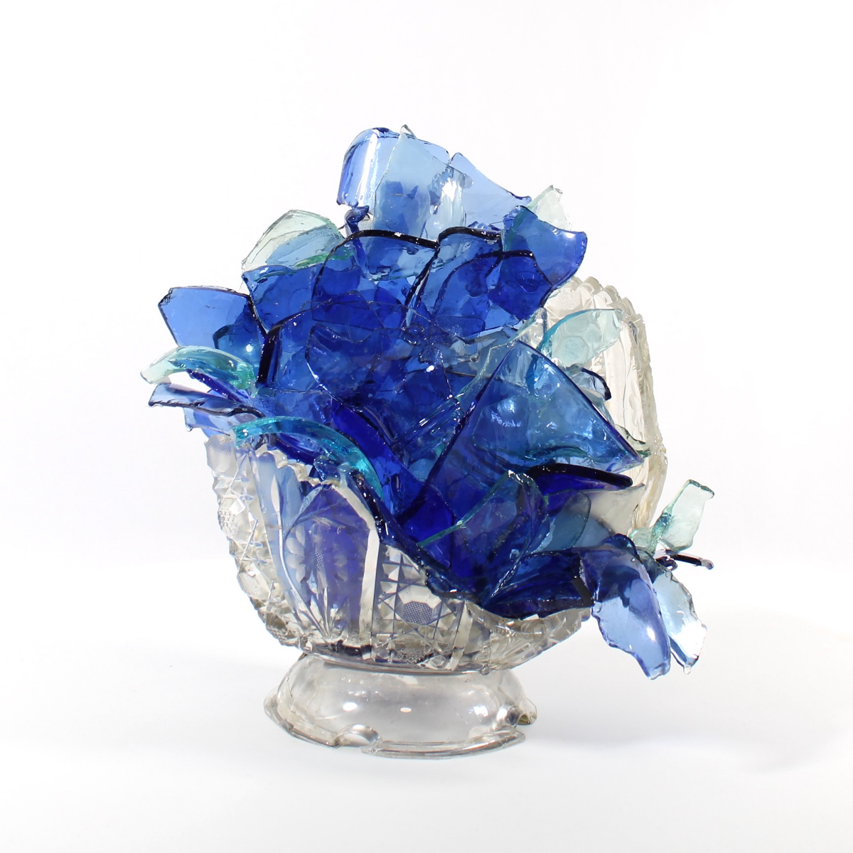 Glass sculpture of a flower made from blue glass pieces on a white background.