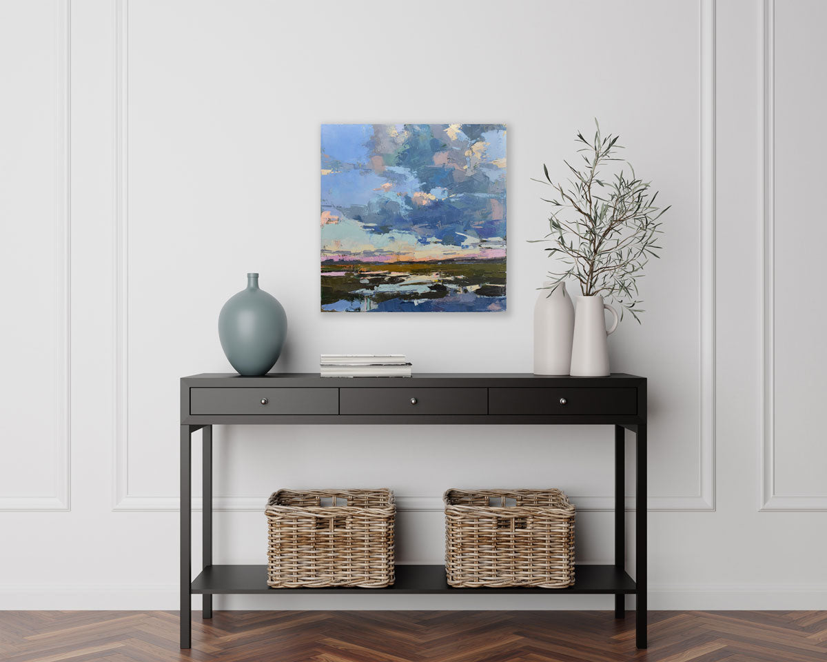 An abstracted landscape painting hangs on a white wall above a black console table with modern decor. 