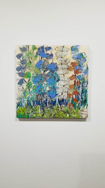 A video of a green and blue abstracted encaustic floral painting hangs on a white wall.