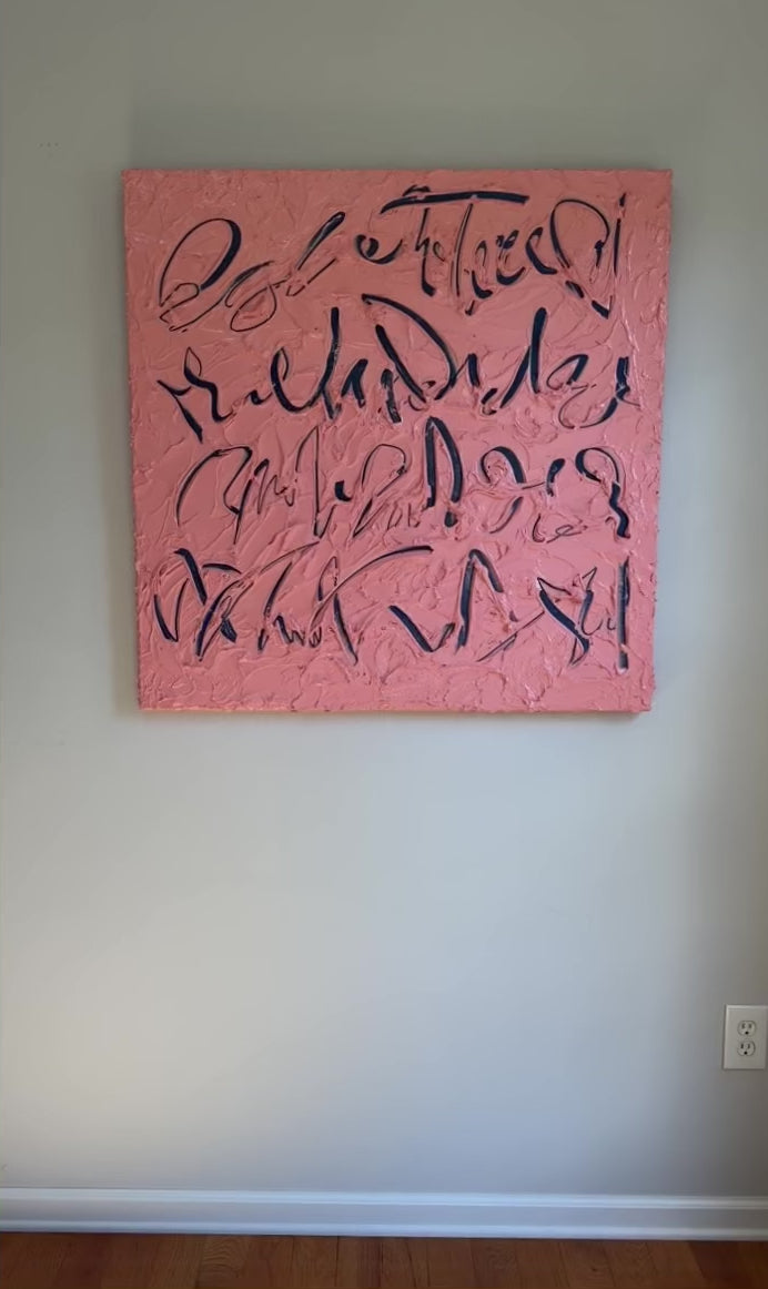 A video of a coral/pink text based painting featuring navy abstract calligraphic lettering, displayed against a neutral light gray wall.