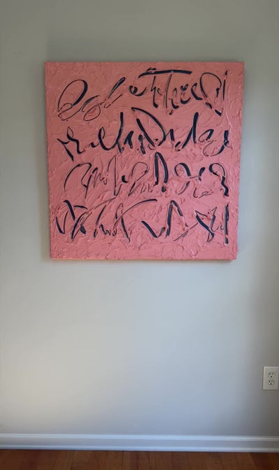 A video of a coral/pink text based painting featuring navy abstract calligraphic lettering, displayed against a neutral light gray wall.