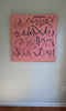 A video of a coral/pink text based painting featuring navy abstract calligraphic lettering, displayed against a neutral light gray wall.