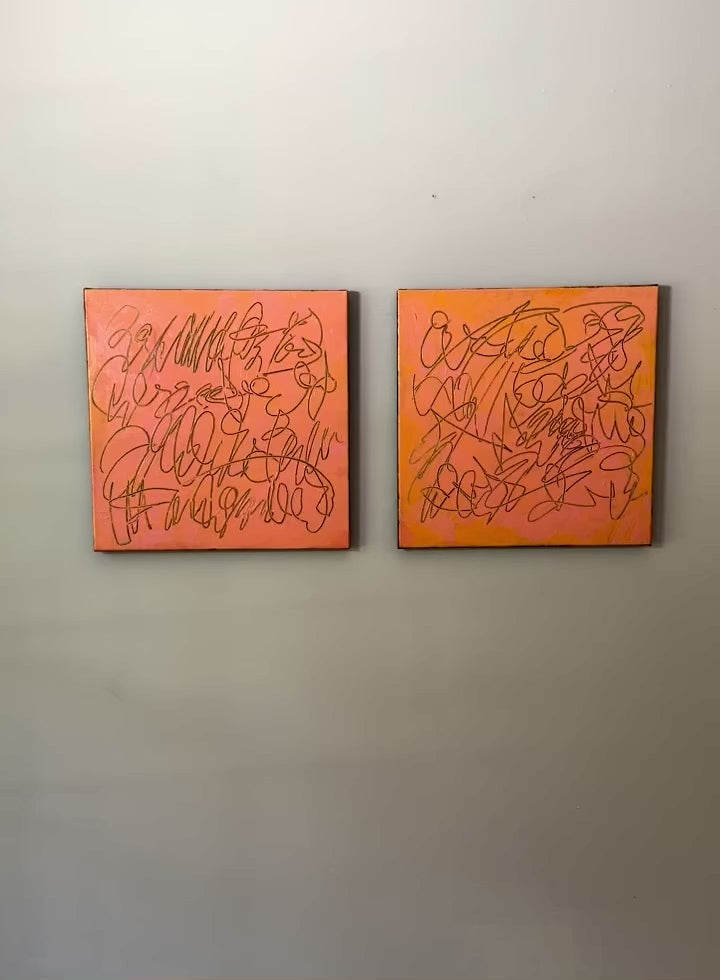 A video of two abstract text based paintings in orange and pink tones hanging on a white wall.