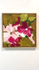 A video of a Framed abstract artwork with colorful flowers on a white wall.