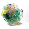 An abstract colorful glass sculpture sits on a white background. 