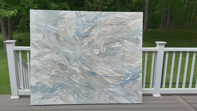 A video of an original abstract painting by Teo Guererra with blue and gray tones on a wooden deck at her studio.